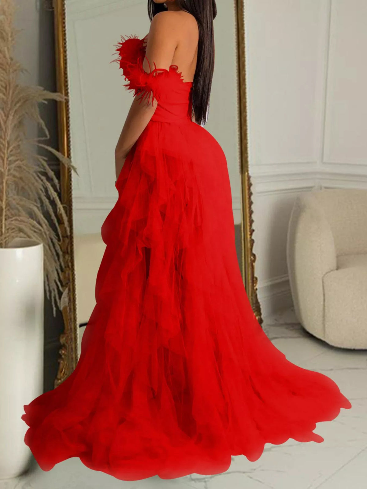 A woman wearing a bright red off-the-shoulder maxi dress with a layered ruffled skirt, photographed indoors in front of a mirror.