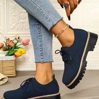 Navy blue shoes worn with light blue jeans on a neutral background