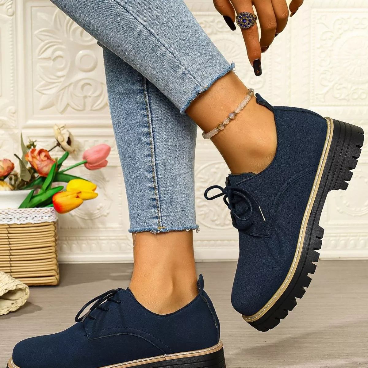 Navy blue shoes worn with light blue jeans on a neutral background