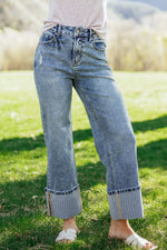 Person wearing light blue jeans standing on grass with a blurred natural background