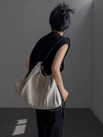 Person holding a beige textured bag against a plain background