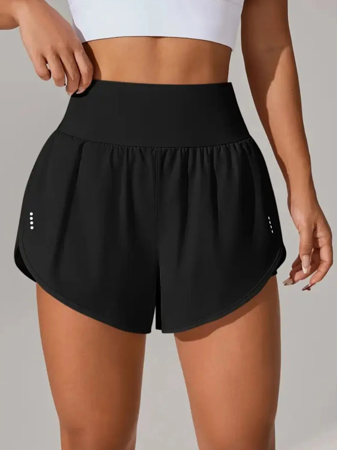 Black athletic shorts worn by a person on a neutral background