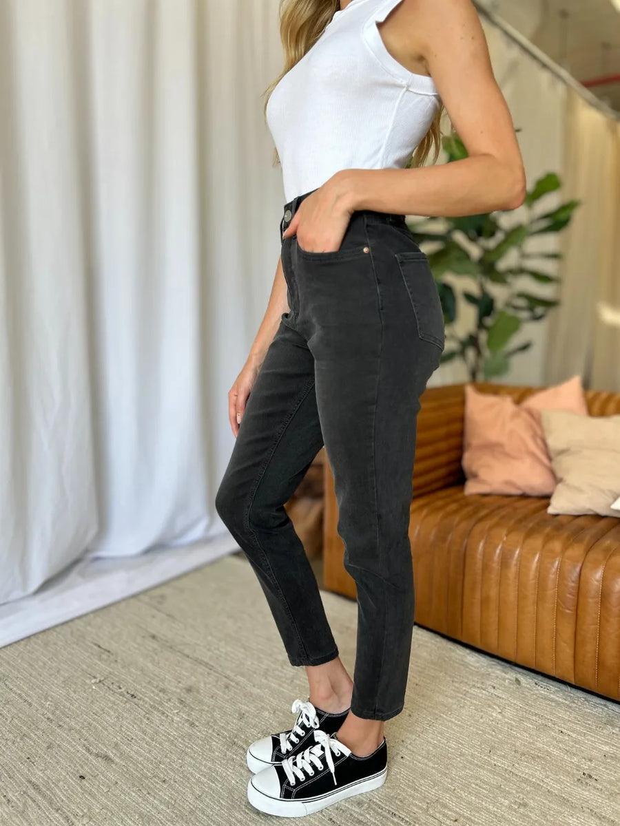 Person wearing black pants and white sneakers in a living room setting