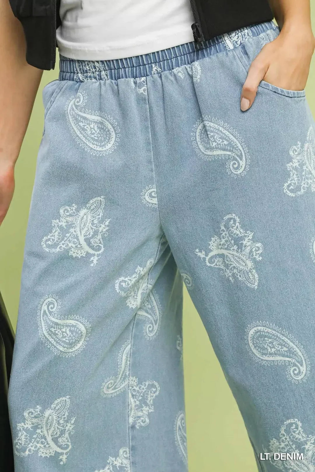Light blue denim pants with white paisley patterns on a green background