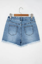 Blue denim shorts on a hanger against a white background
