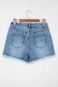 Blue denim shorts on a hanger against a white background