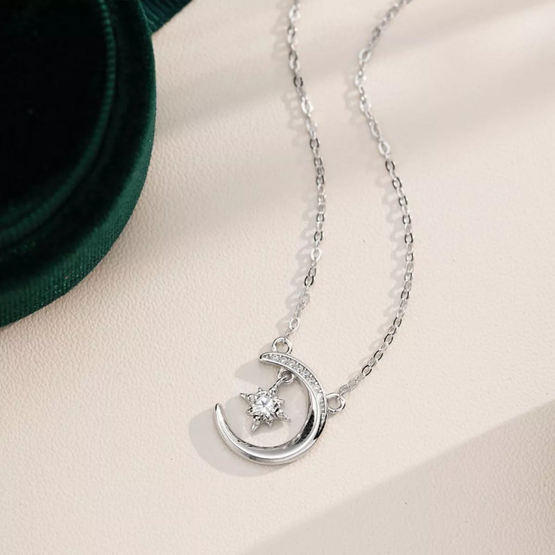 Silver necklace with a moon and star pendant on a beige surface.