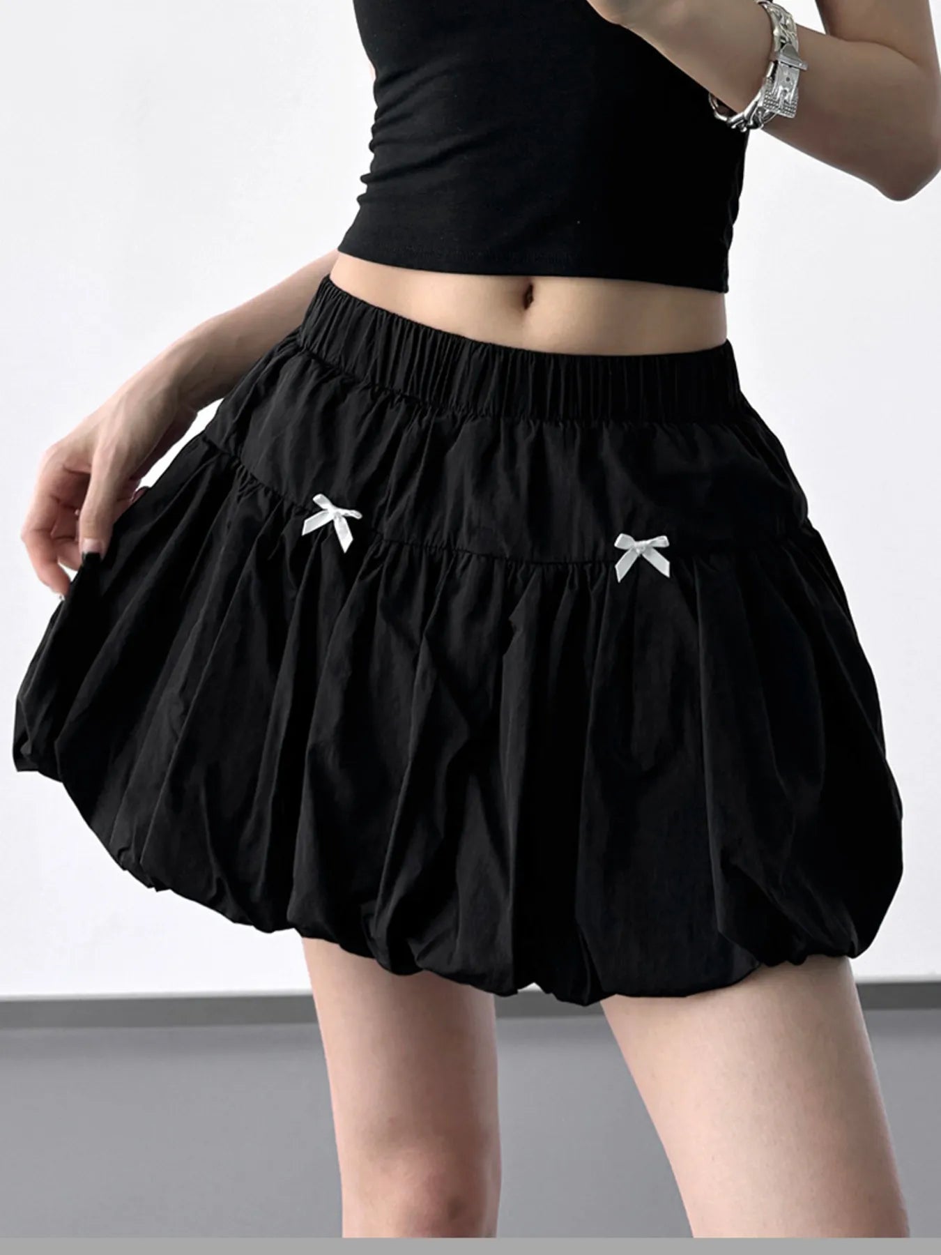 Black skirt with white bow details worn by a person on a plain background