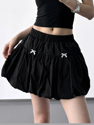 Black skirt with white bow details worn by a person on a plain background