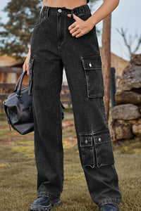 Person wearing black cargo pants holding a black bag outdoors.