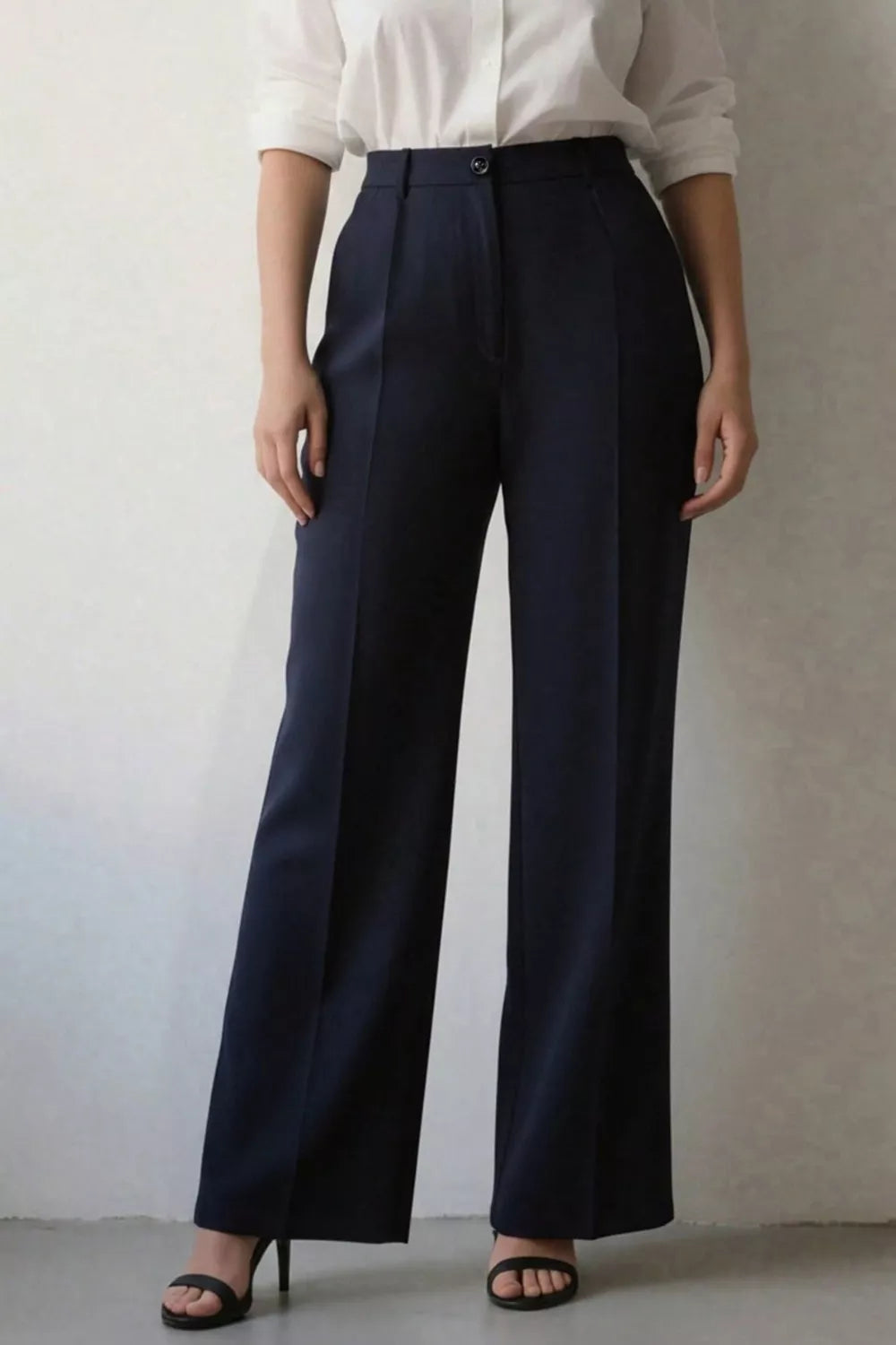 Person wearing navy wide-leg pants and a white shirt against a neutral background