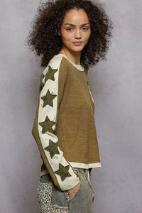 Woman wearing a green sweater with star patterns on a gray background