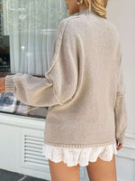 Person wearing a beige sweater with lace trim and white shorts outdoors.