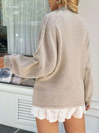 Person wearing a beige sweater with lace trim and white shorts outdoors.