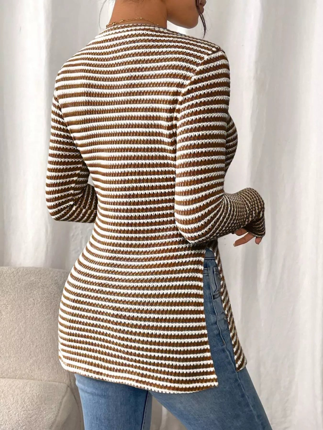 Person wearing a brown and white striped long-sleeve top with a blurred background