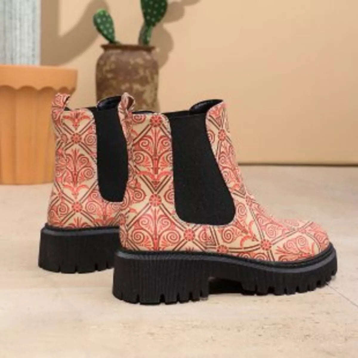 Patterned ankle boots with black soles on a neutral background