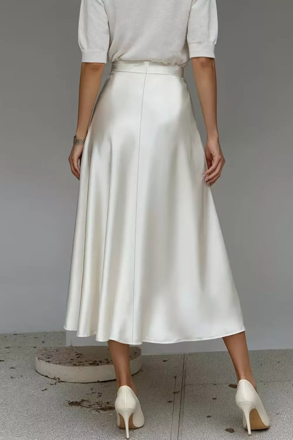 Person wearing a white skirt and high heels on a plain background