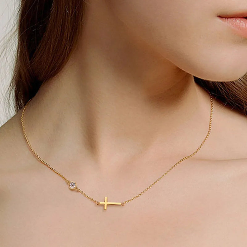Gold necklace with a cross pendant worn by a person