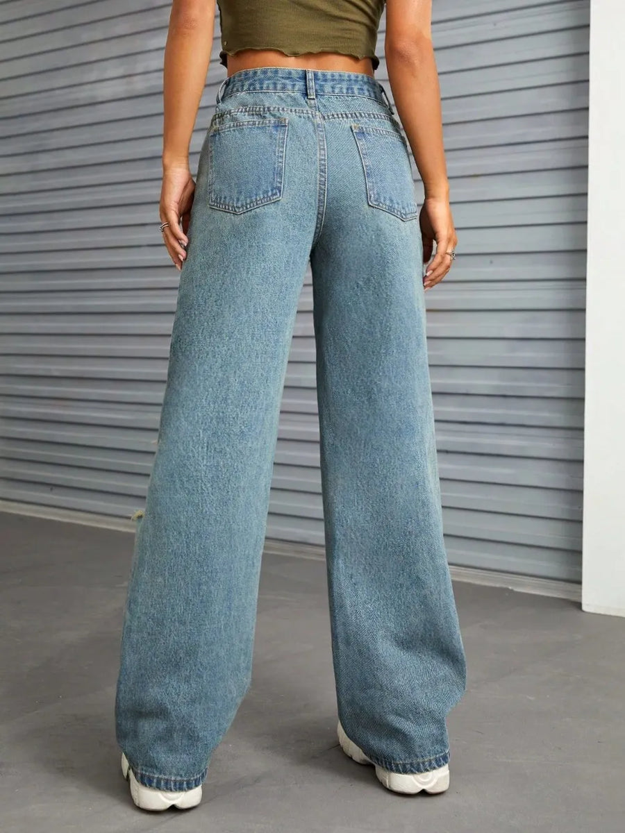 Person wearing blue jeans standing in front of a gray metallic door.