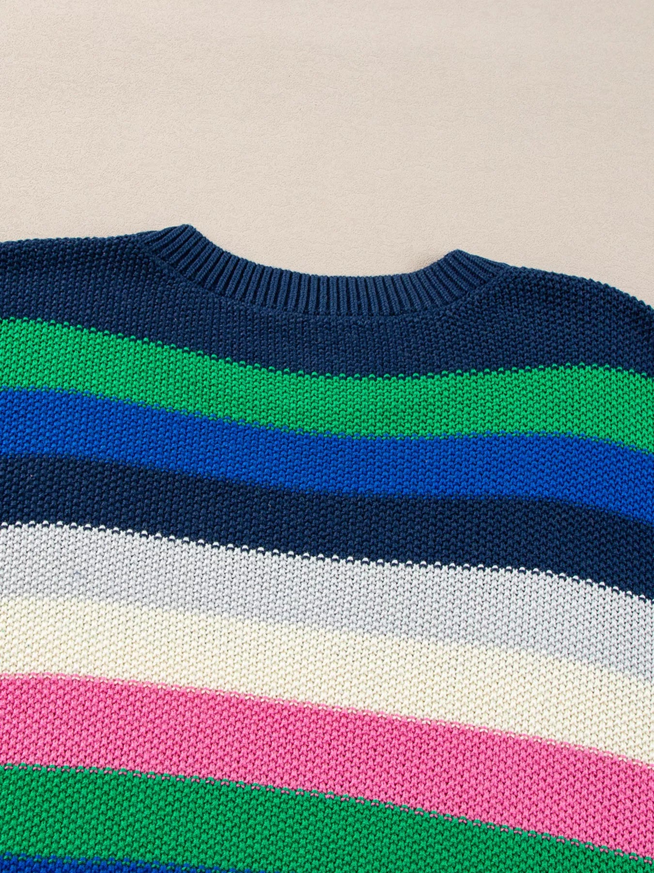 Close-up of a sweater with colorful horizontal stripes on a beige background