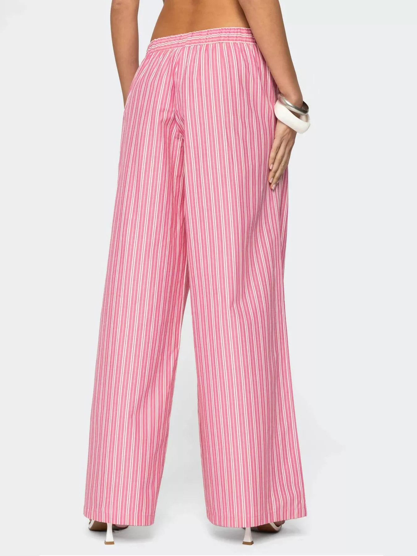 Pink and white striped pants worn by a person on a white background