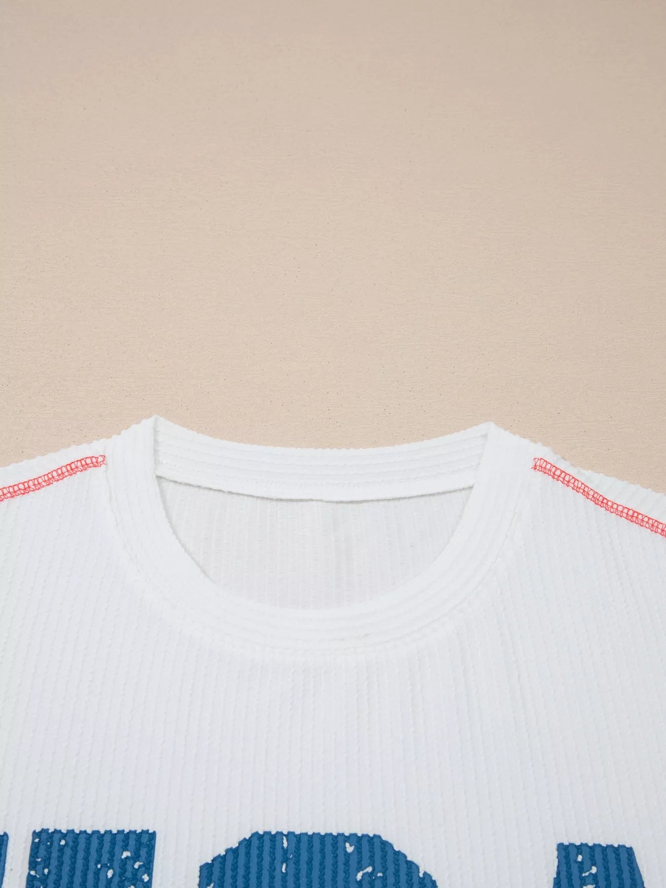 Close-up of a white shirt with blue text on a beige background