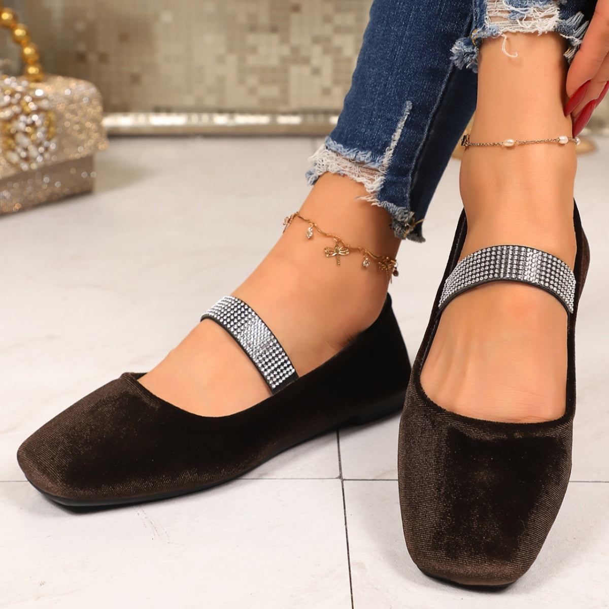 Brown flat shoes with decorative straps worn by a person on a light background