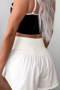 Person wearing a black crop top and white skirt against a neutral background