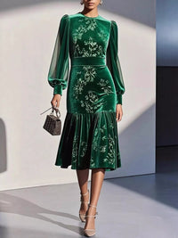 Green velvet dress with floral embroidery worn by a model against a neutral background