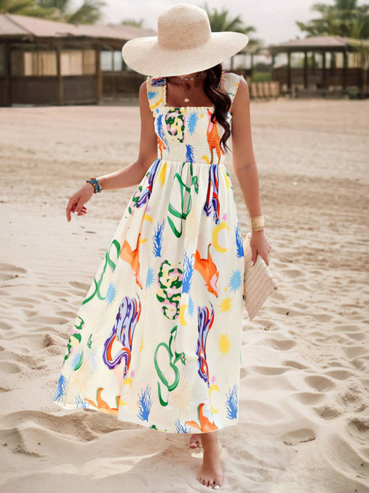 Woman in a colorful dress and sun hat on a sandy beach.