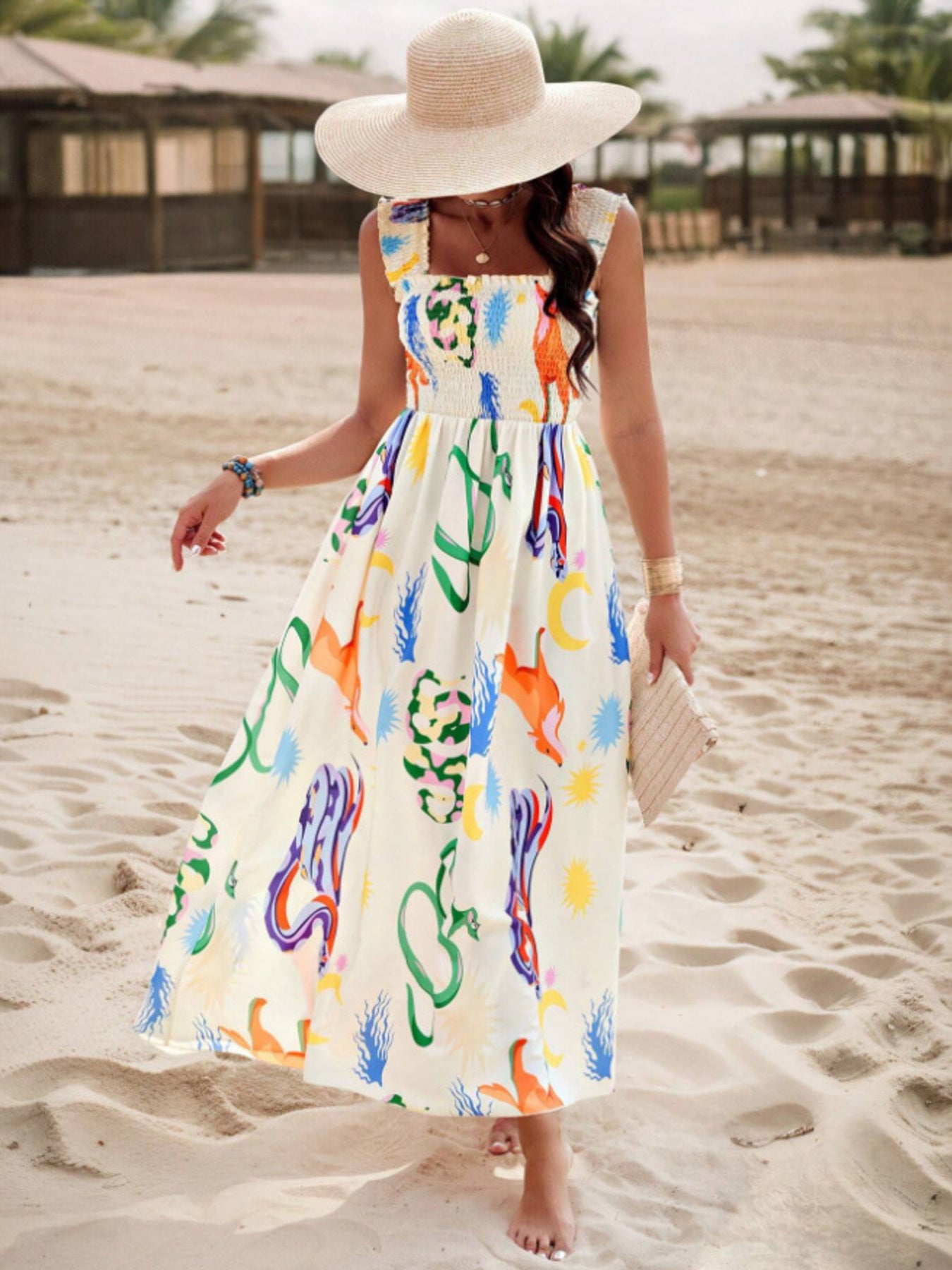 Woman in a colorful dress and sun hat on a sandy beach.