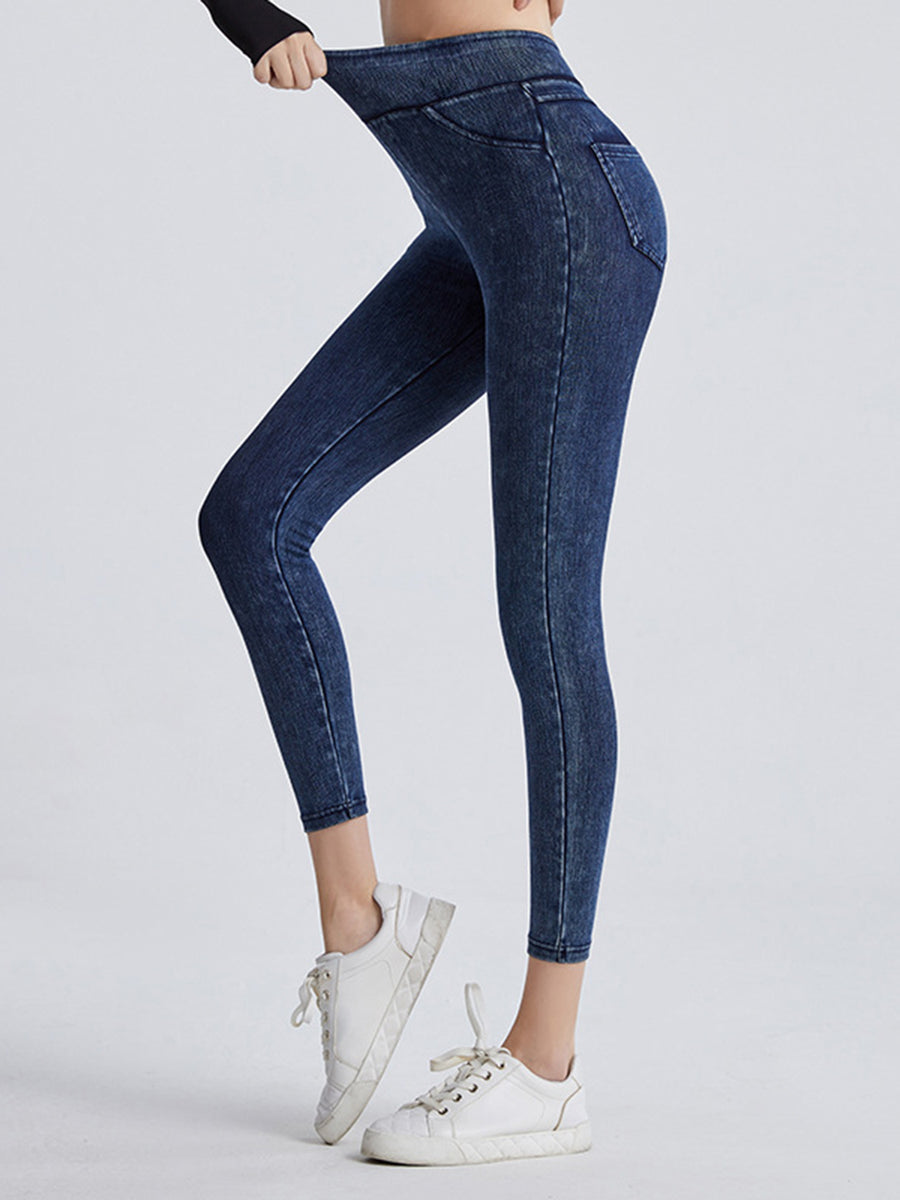 Person wearing blue jeans and white sneakers on a light gray background