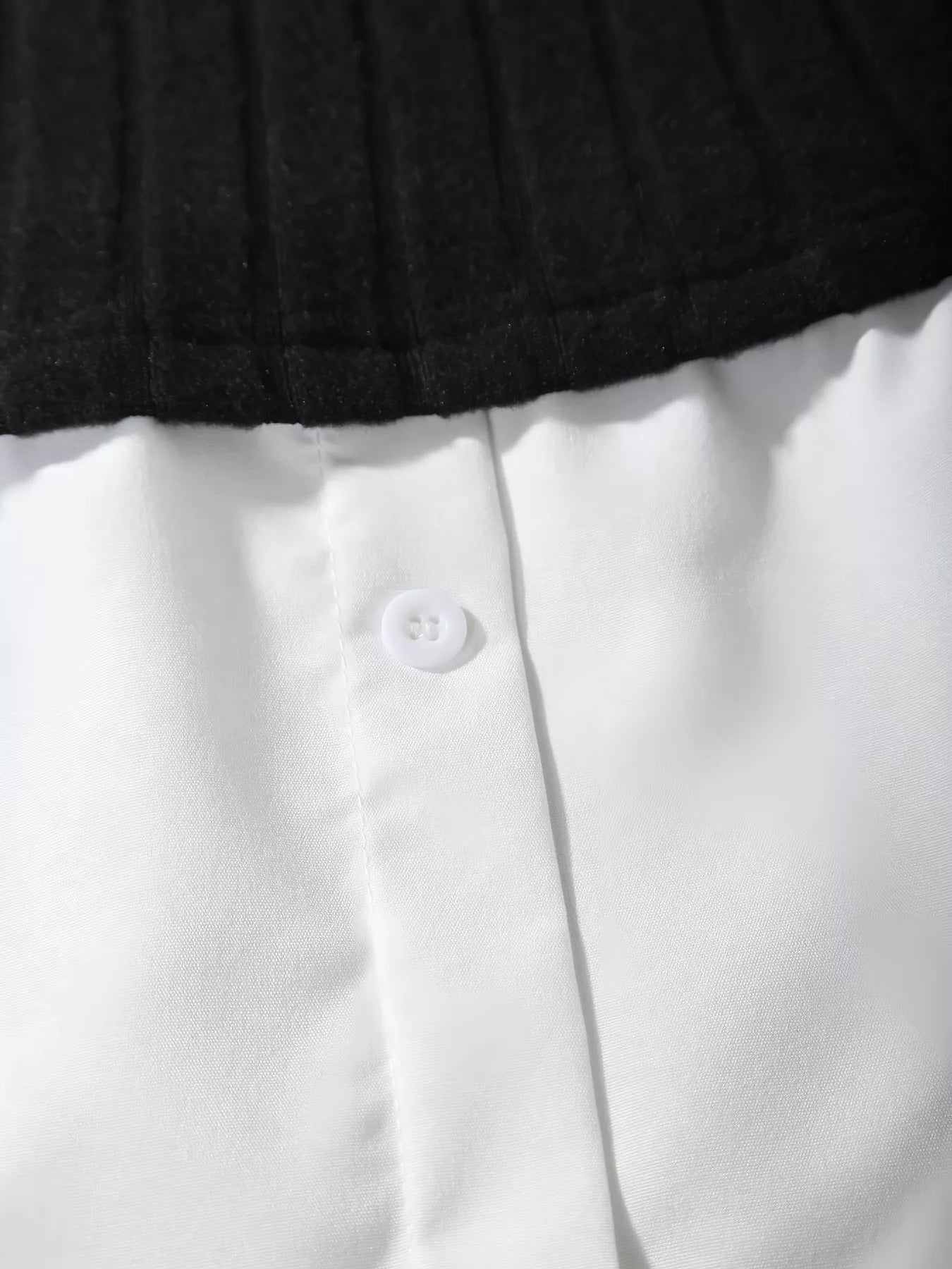 Close-up of a white shirt with a button and black collar.