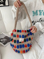 Colorful pom-pom bag held by a person on a white couch