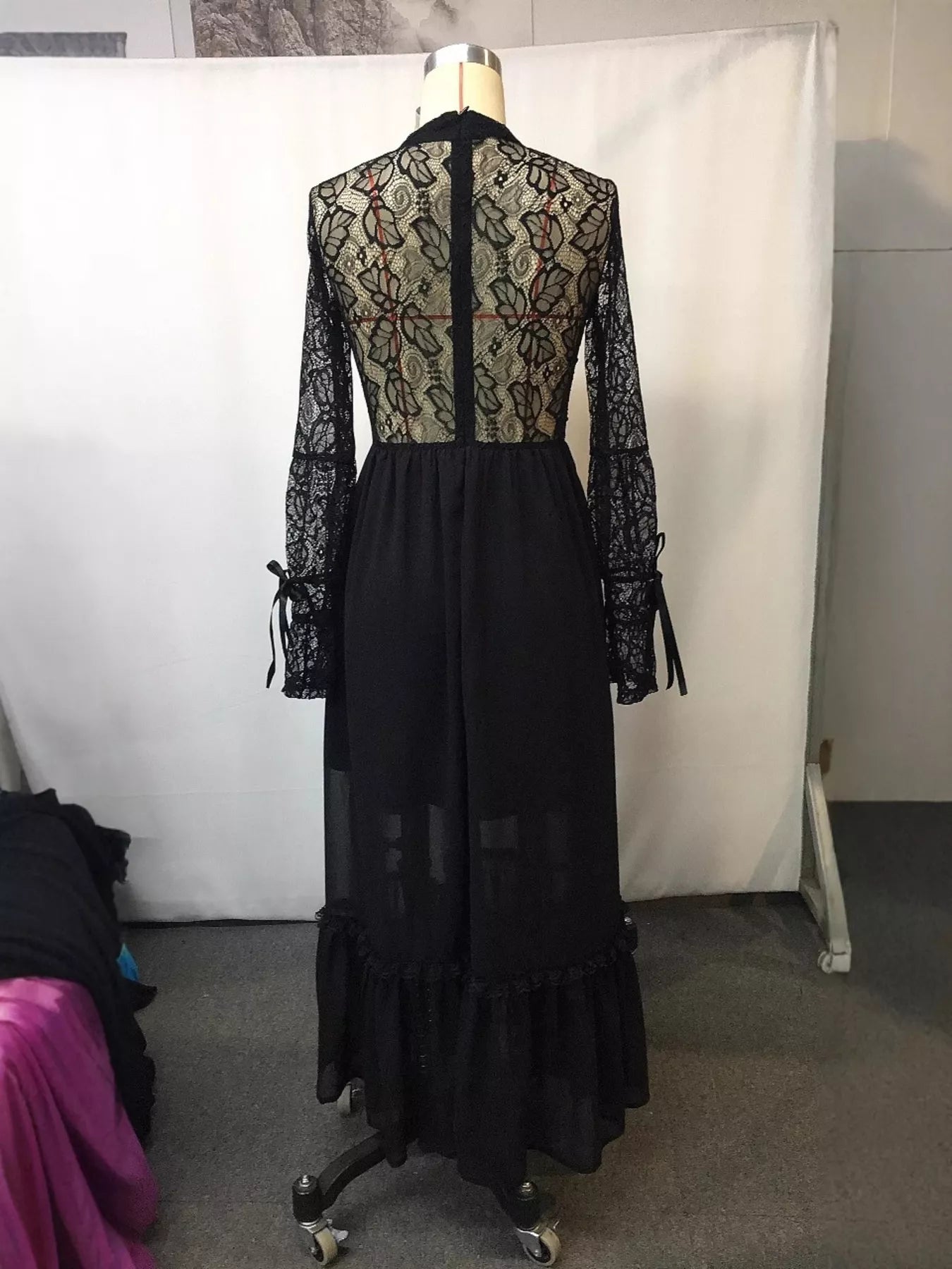 Black lace dress on a mannequin against a white backdrop