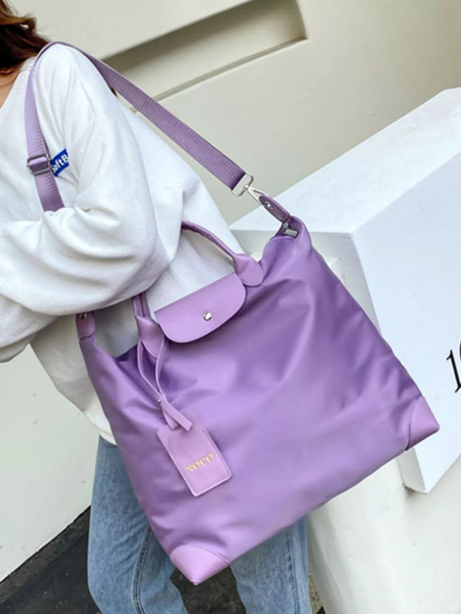 Person holding a purple handbag with a visible brand logo against a neutral background
