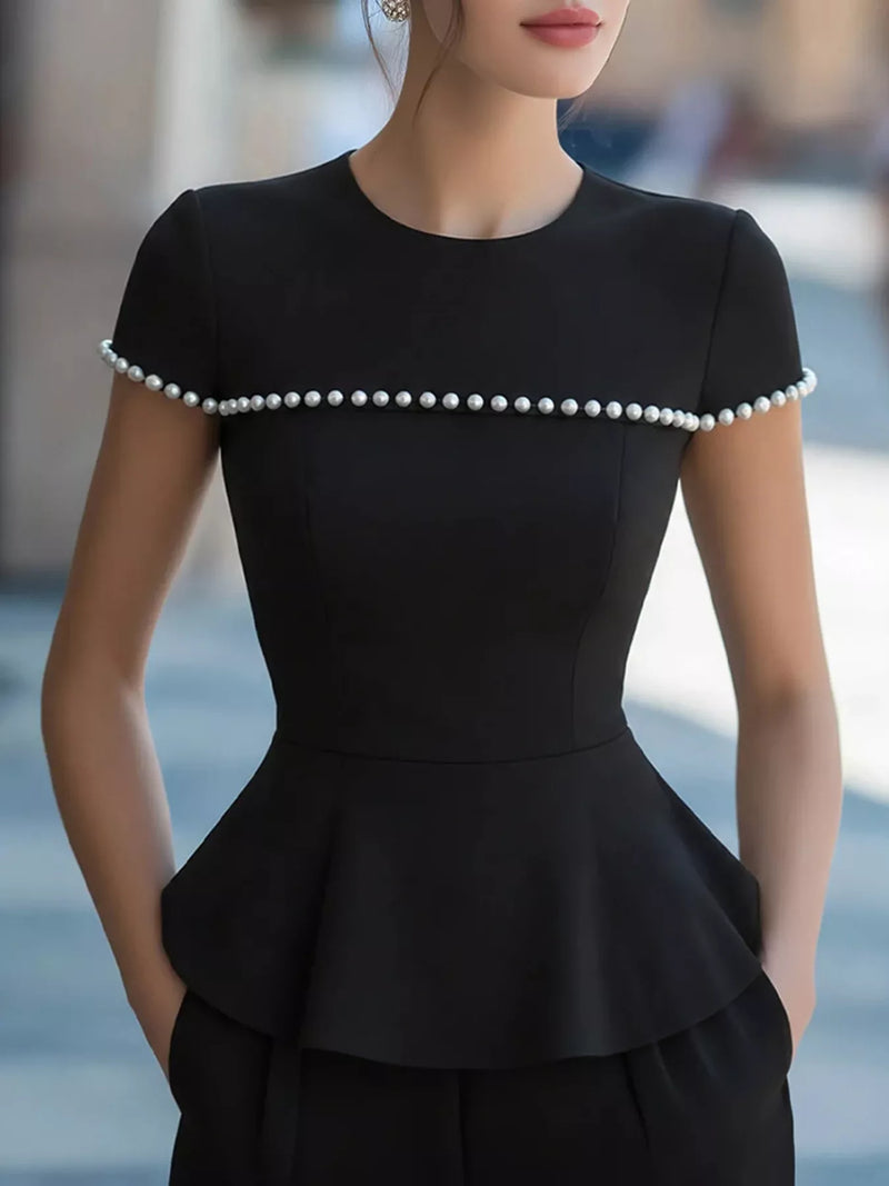 Black dress with pearl details worn by a model outdoors
