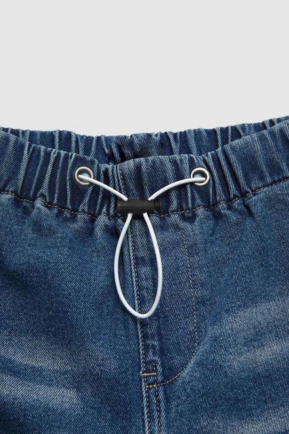 Close-up of blue denim shorts with drawstring on a light gray background
