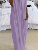 Person wearing a purple jumpsuit standing in a room with white bedding.