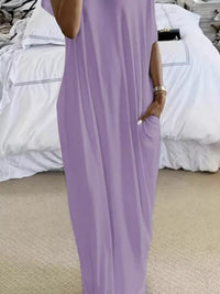 Person wearing a purple jumpsuit standing in a room with white bedding.