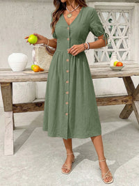 Woman wearing a green dress holding an apple in a casual setting.