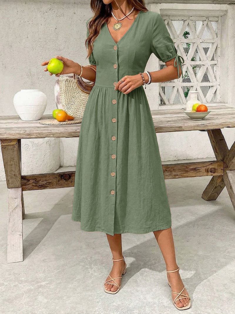 Woman wearing a green dress holding an apple in a casual setting.