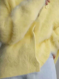 Close-up of a yellow fur coat with a button detail.