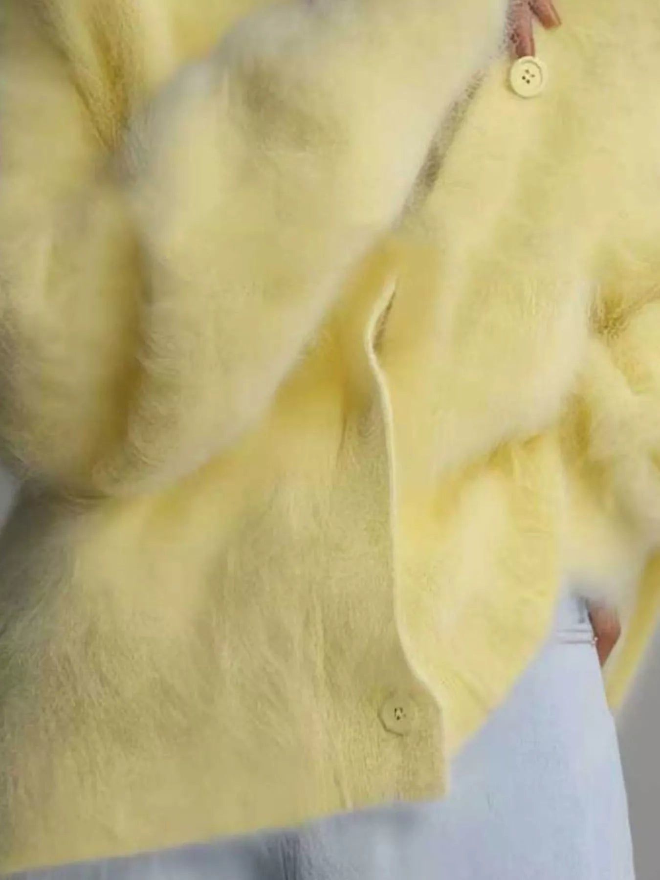 Close-up of a yellow fur coat with a button detail.