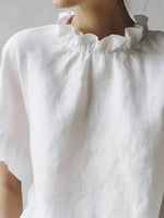 Close-up of a white blouse with ruffled collar on a plain background