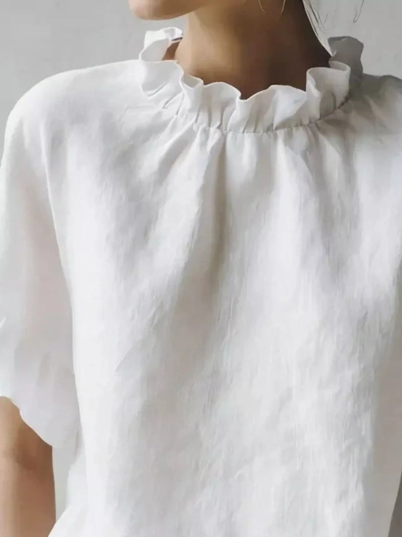 Close-up of a white blouse with ruffled collar on a plain background