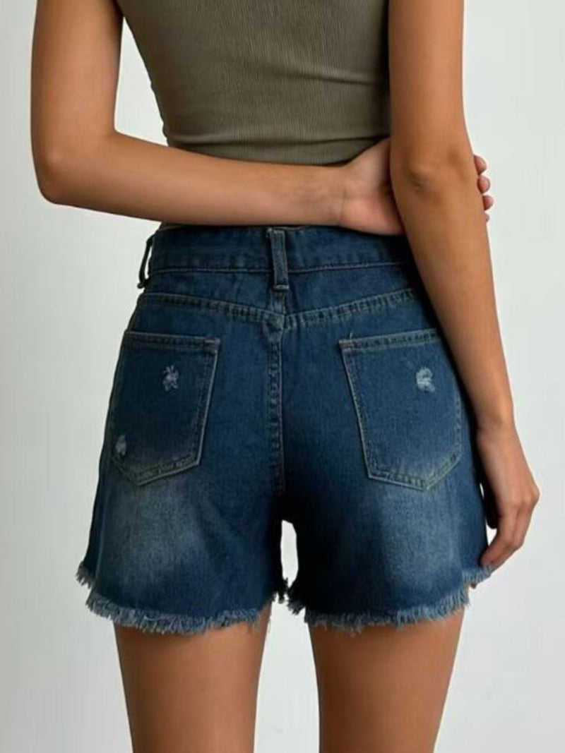 Person wearing blue denim shorts on a plain background