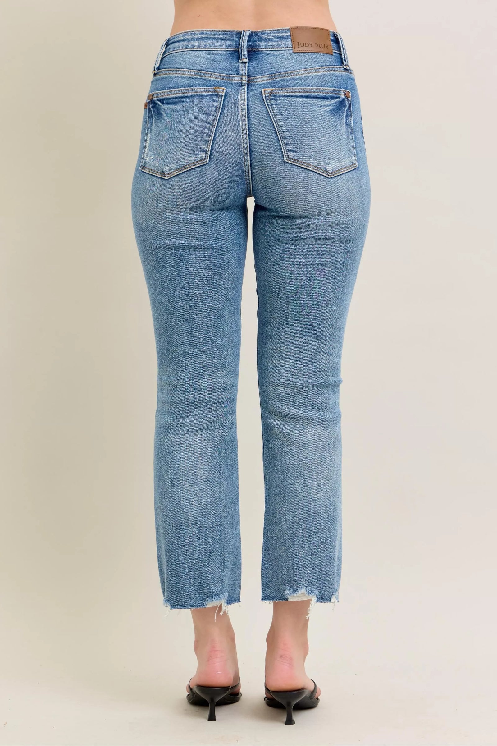 Blue jeans worn by a person on a beige background