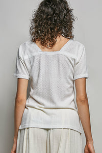 Person wearing a light-colored textured top and pants against a plain background