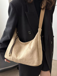 Person holding a beige handbag with a plain background